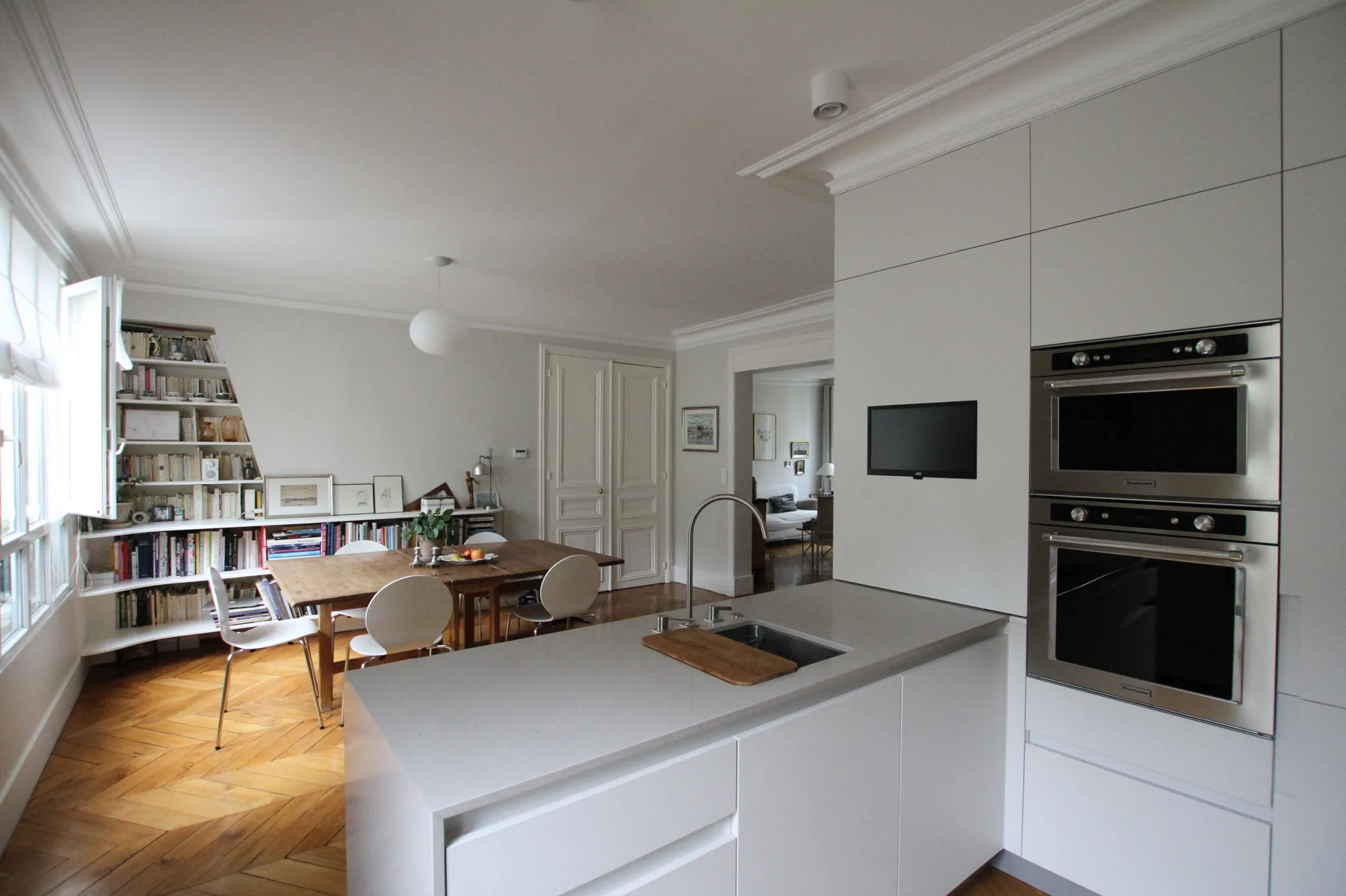 Cuisine et séjour réunis dans un même mouvement, parquet à chevrons d'origine, appartement Paris 16e Iéna