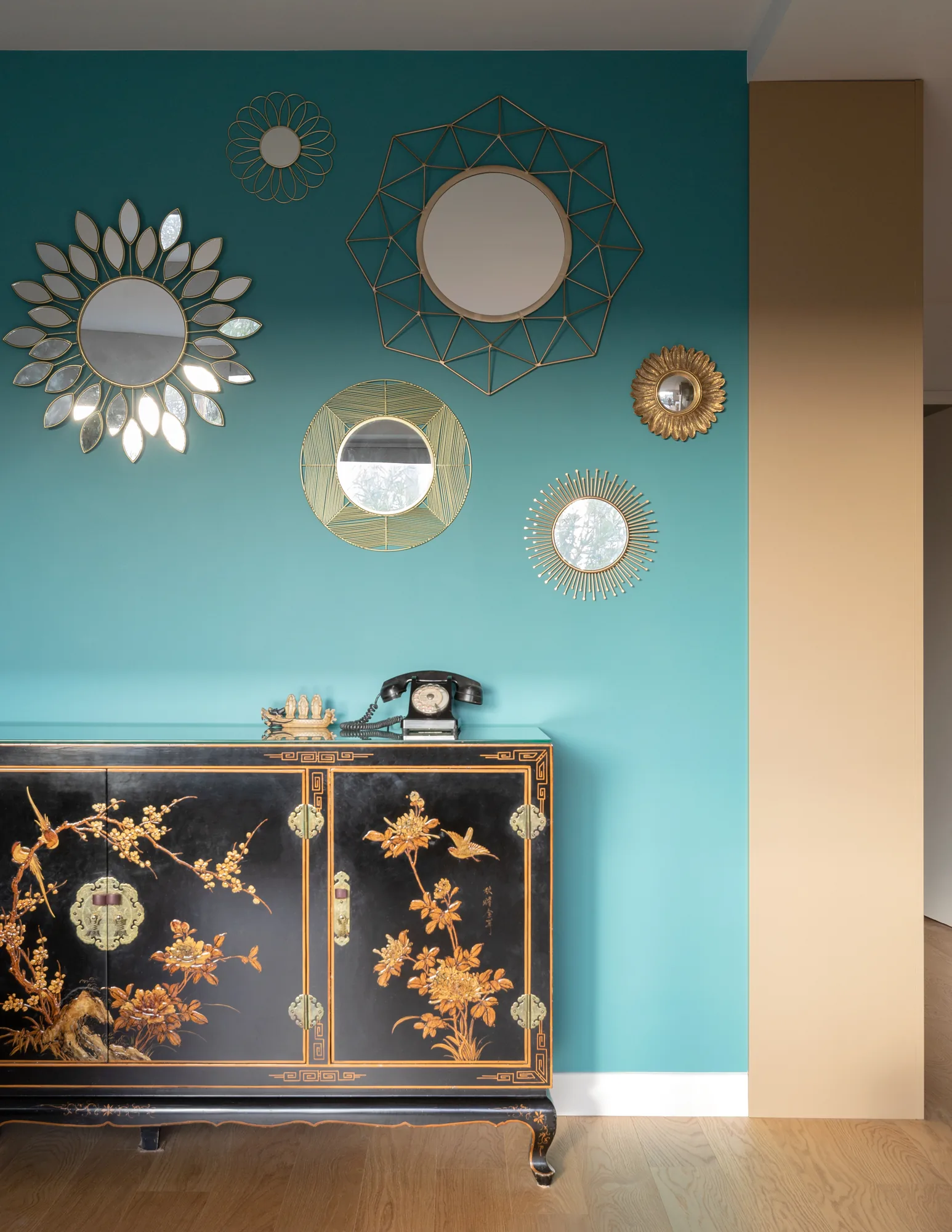Salon au mur turquoise, collection de miroirs soleil et cabinet laqué, appartement Vanves