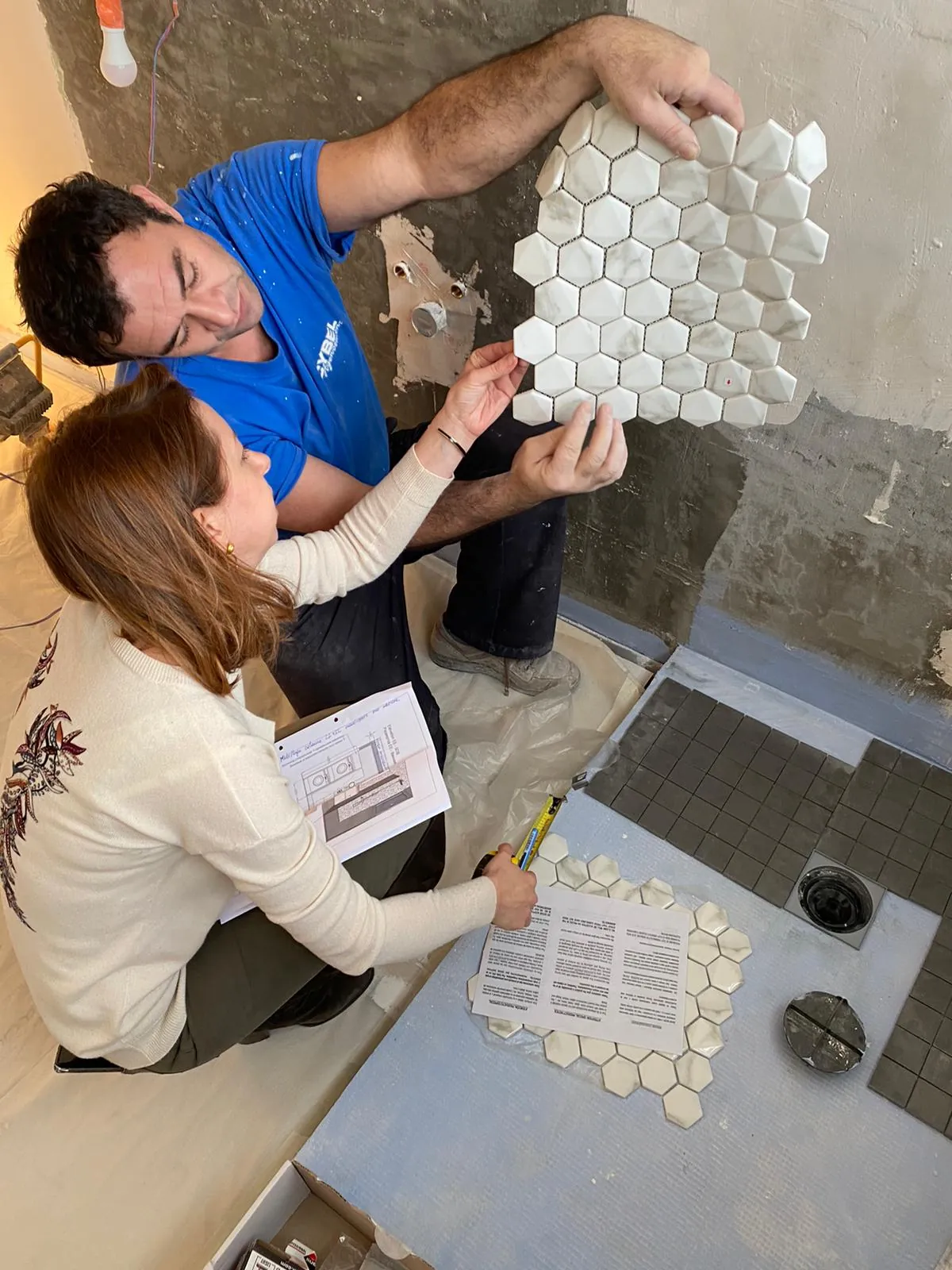 Choix d'une mosaïque de marbre hexagonale sur le chantier, avec l'artisan carreleur