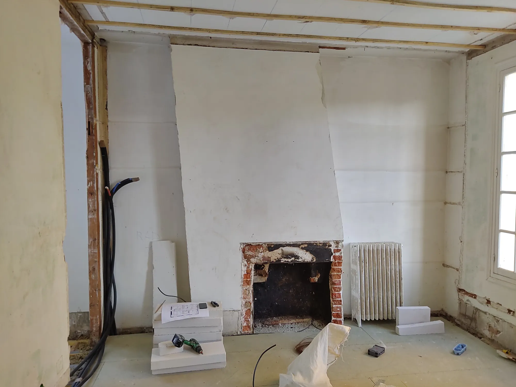La même pièce pendant les travaux, cheminée en brique mise à nu et structure reprise